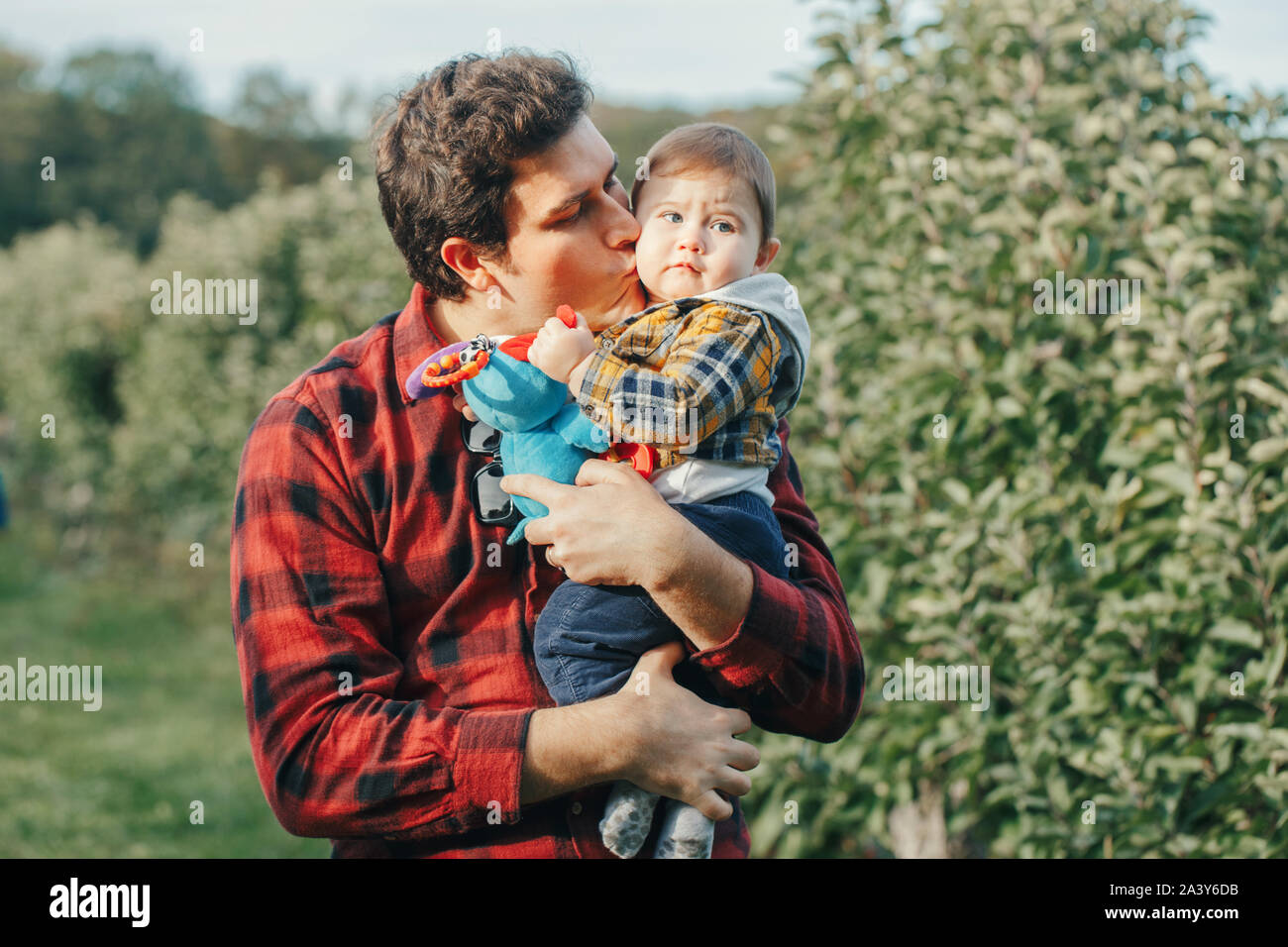 Caucasian father hugging kissing baby boy. Parent holding carrying child son. Authentic lifestyle touching tender moment. Single dad family life conce Stock Photo