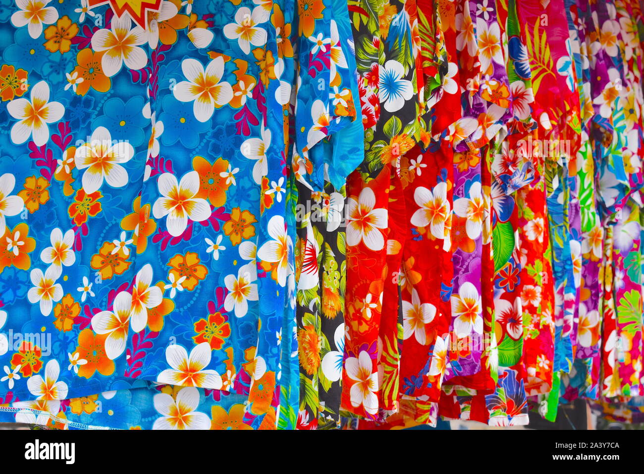 Short sleeve shirts with bright exotic flower print hanging on a market stall. Typical summer coastal vacation clothing worldwide. Europe Stock Photo
