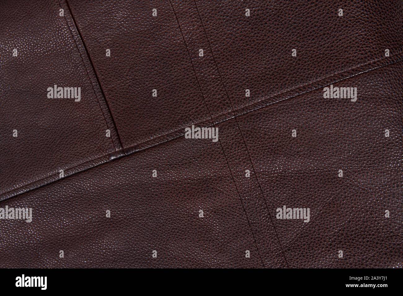 Dark brown stitched leather background. Asymmetric seams. Rough surface with free space. Expensive material sample. Handwork. Seat upholstery or leath Stock Photo