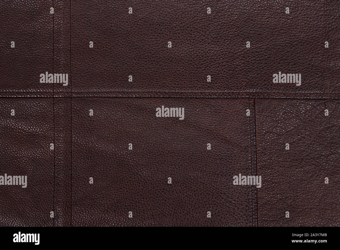 Dark brown stitched leather background. Asymmetric seams. Rough surface with free space. Expensive material sample. Handwork. Seat upholstery or leath Stock Photo