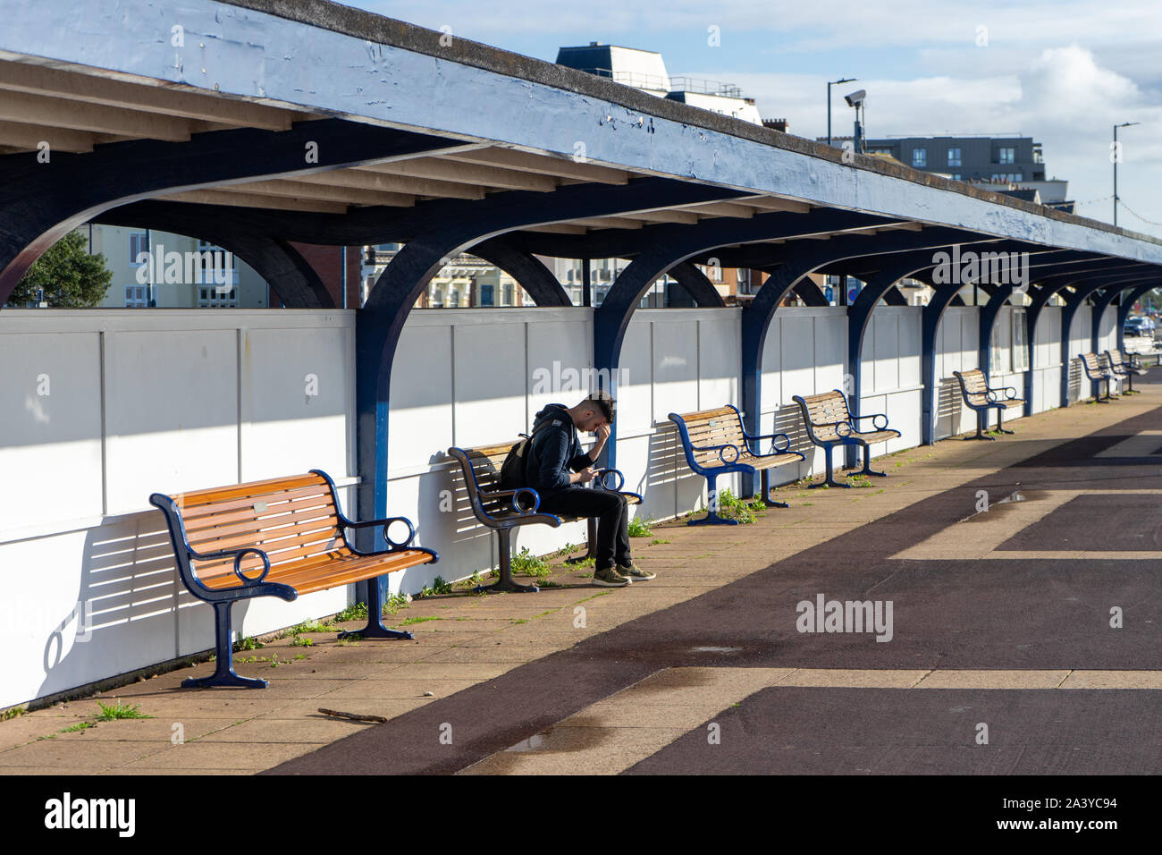 A young man sitting alone on a bench with his head in his hands Stock Photo