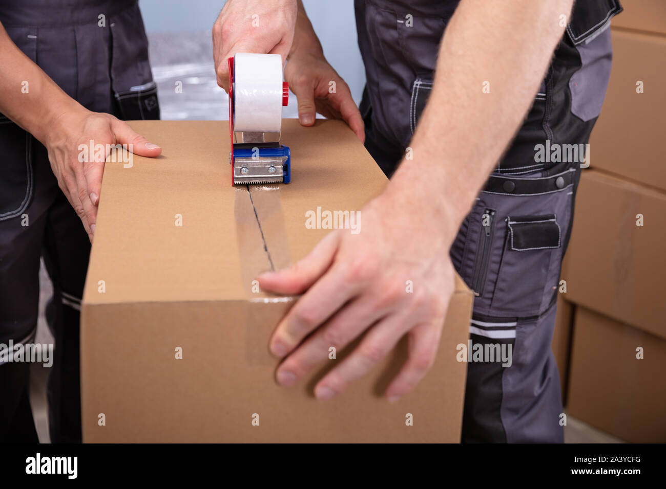 Movers Packaging Cardboard Boxes With Tape Gun Dispenser To Move In New