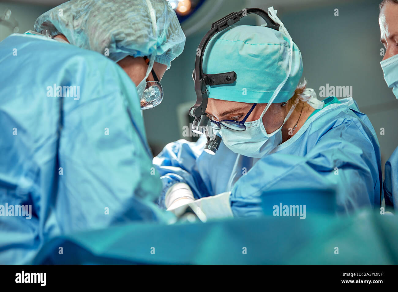 Group of surgeons looking at patient on operation table during their ...