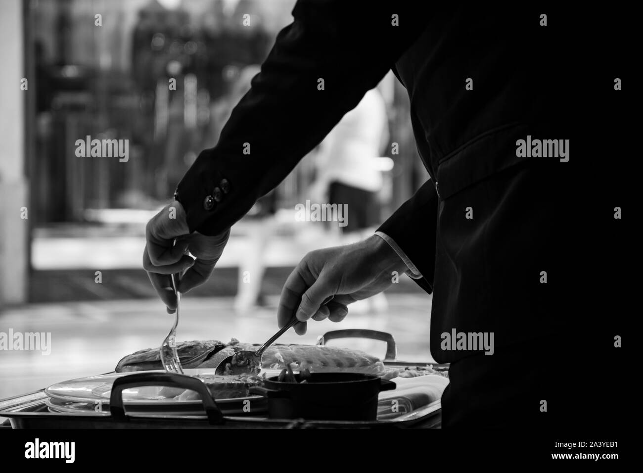 Expert waiter filleting and serving a delicious grilled sea bream in an elegant restaurant. Stock Photo