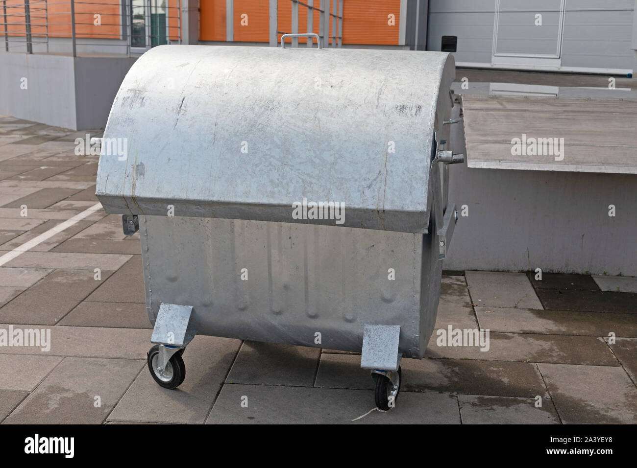 Silver Industrial Dumpster Container in Front of Warehouse Stock Photo