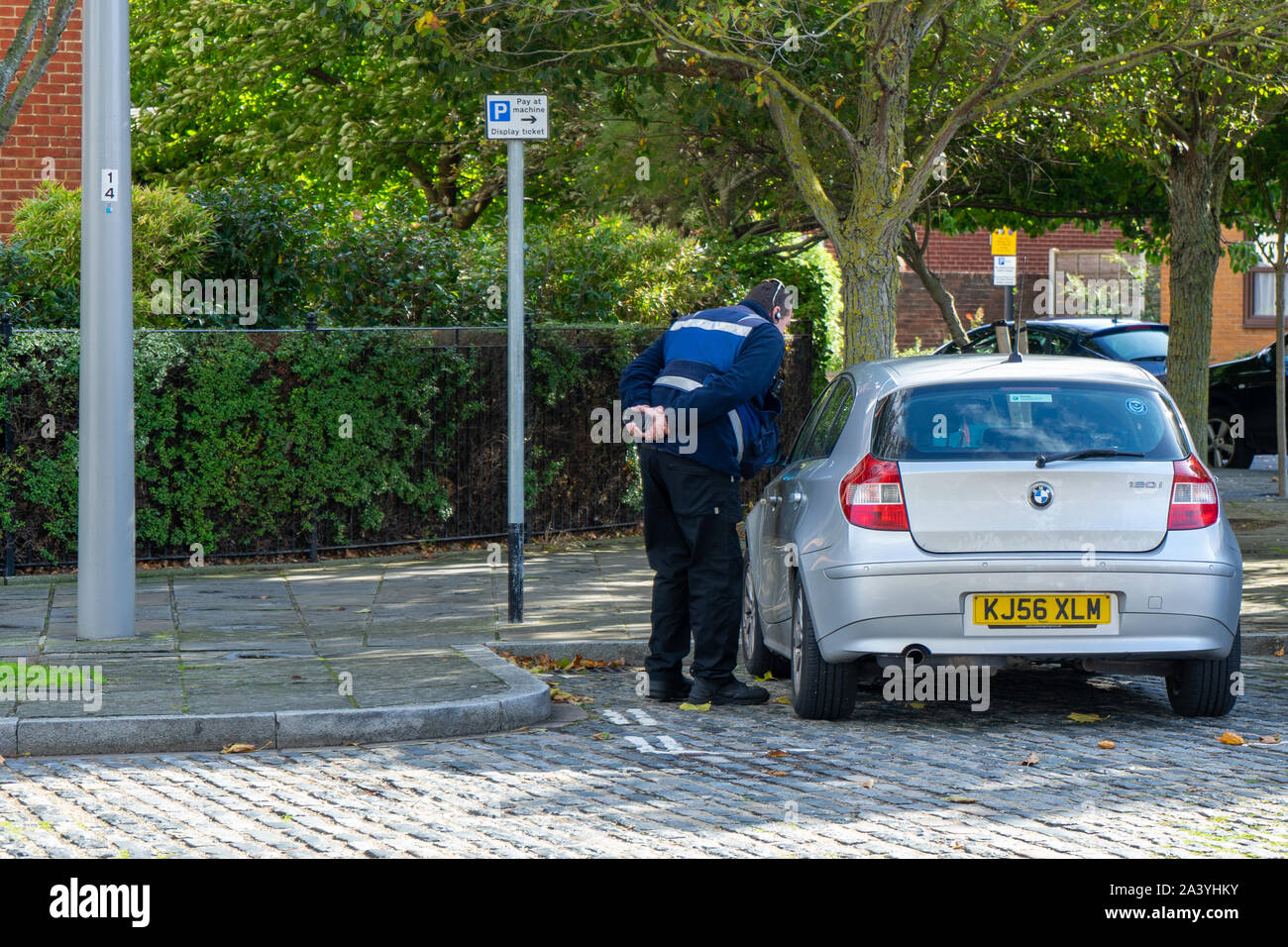 A traffic warden issuing a parking ticket on a parked car Stock Photo