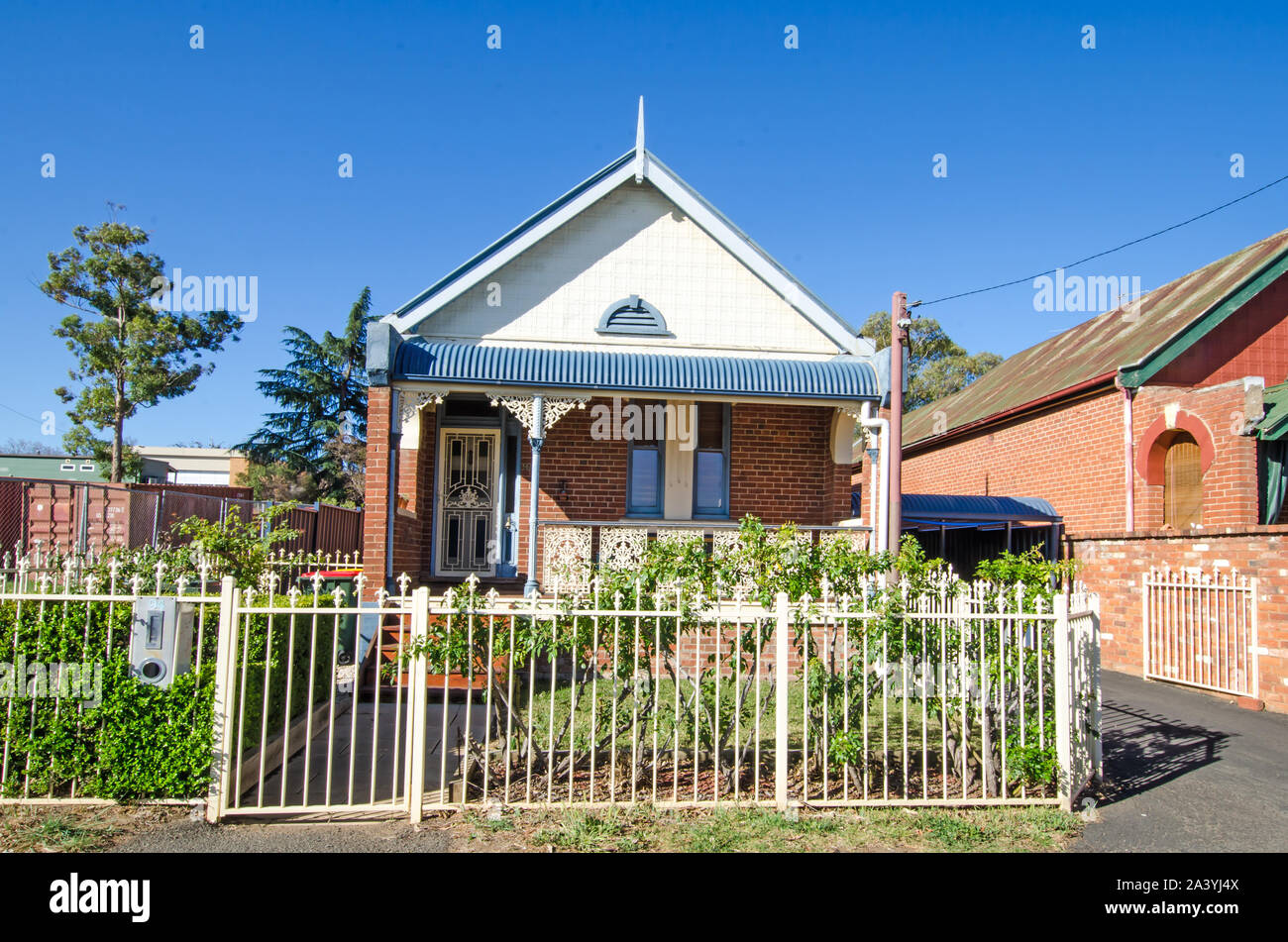 A narrow fronted late Victorian single storey cottage with iron railing fence. Stock Photo