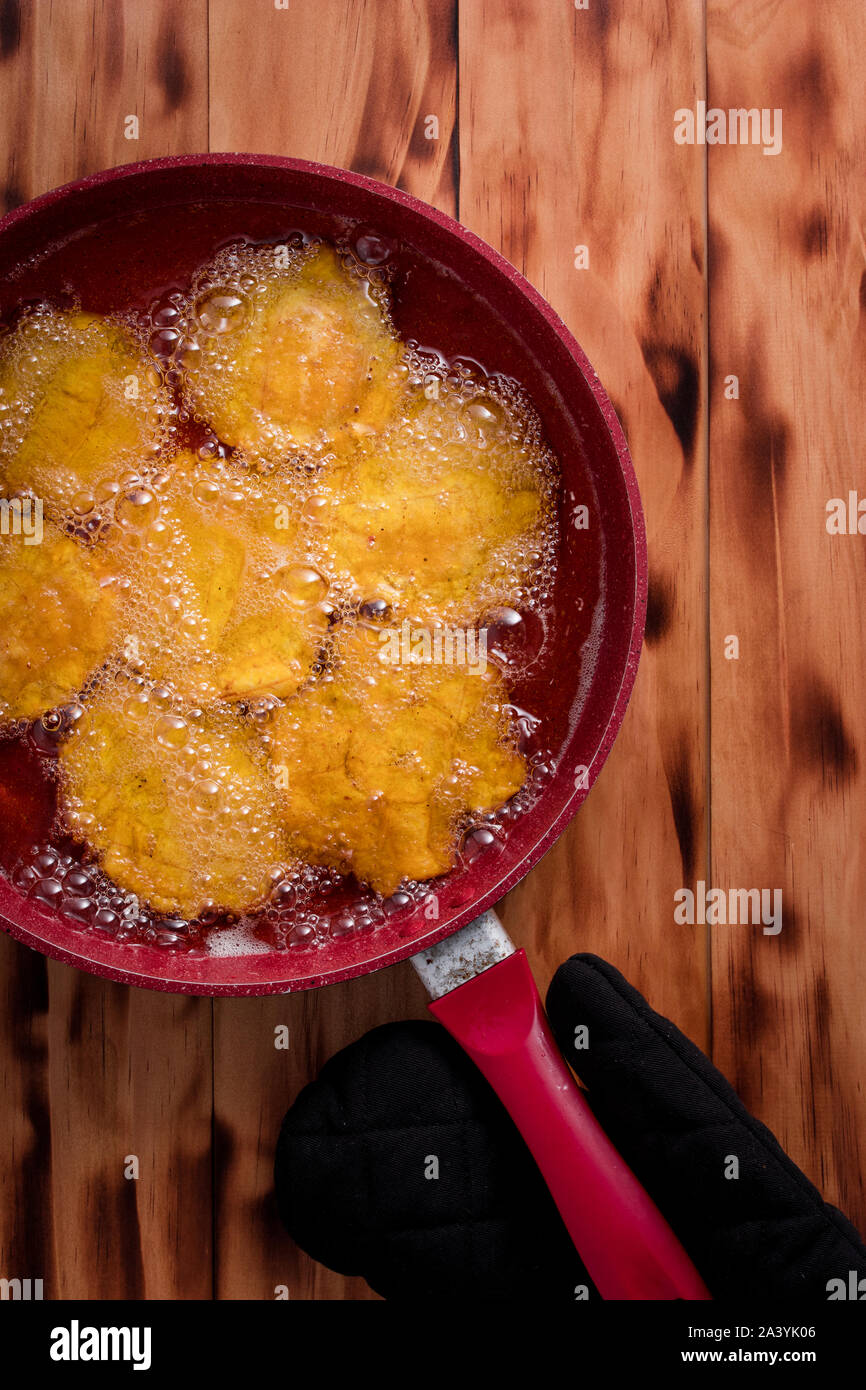 Deep fried banana fritters in a red frying pan Stock Photo - Alamy