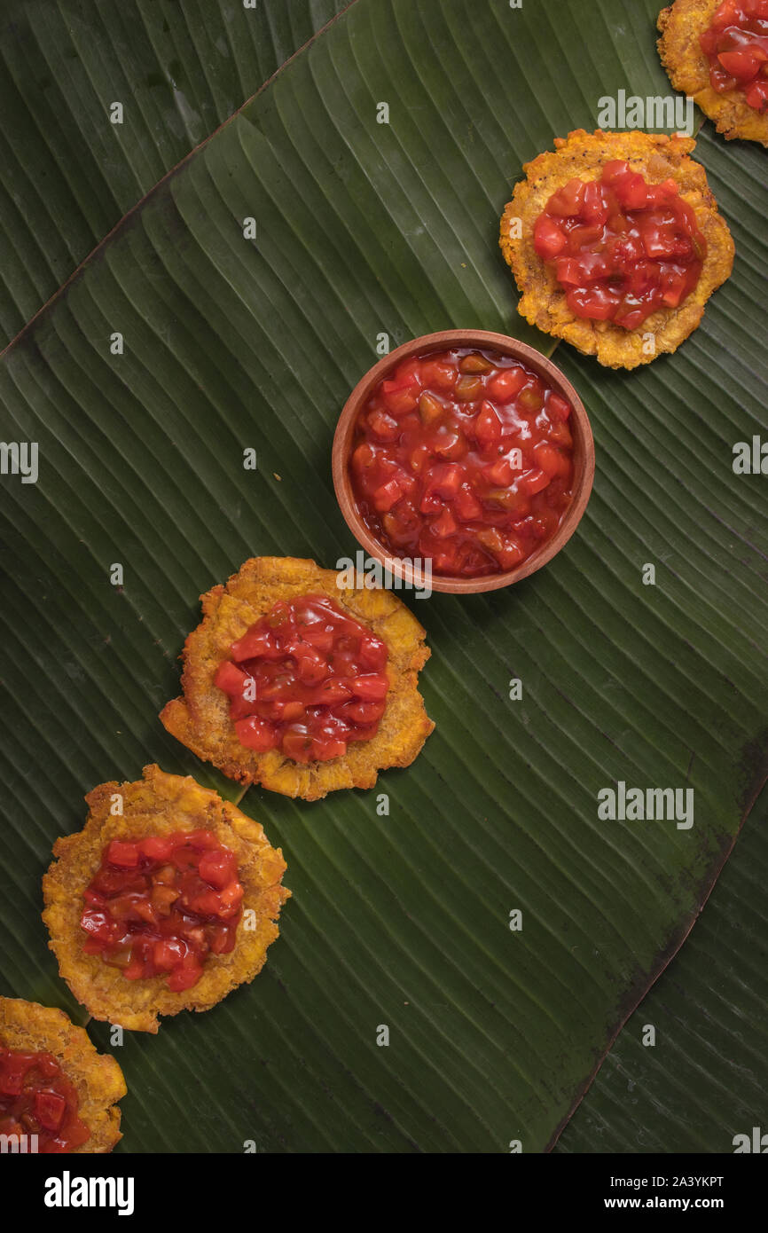 Deep fried banana fritters on banana leaves with tomato chutney (rustic