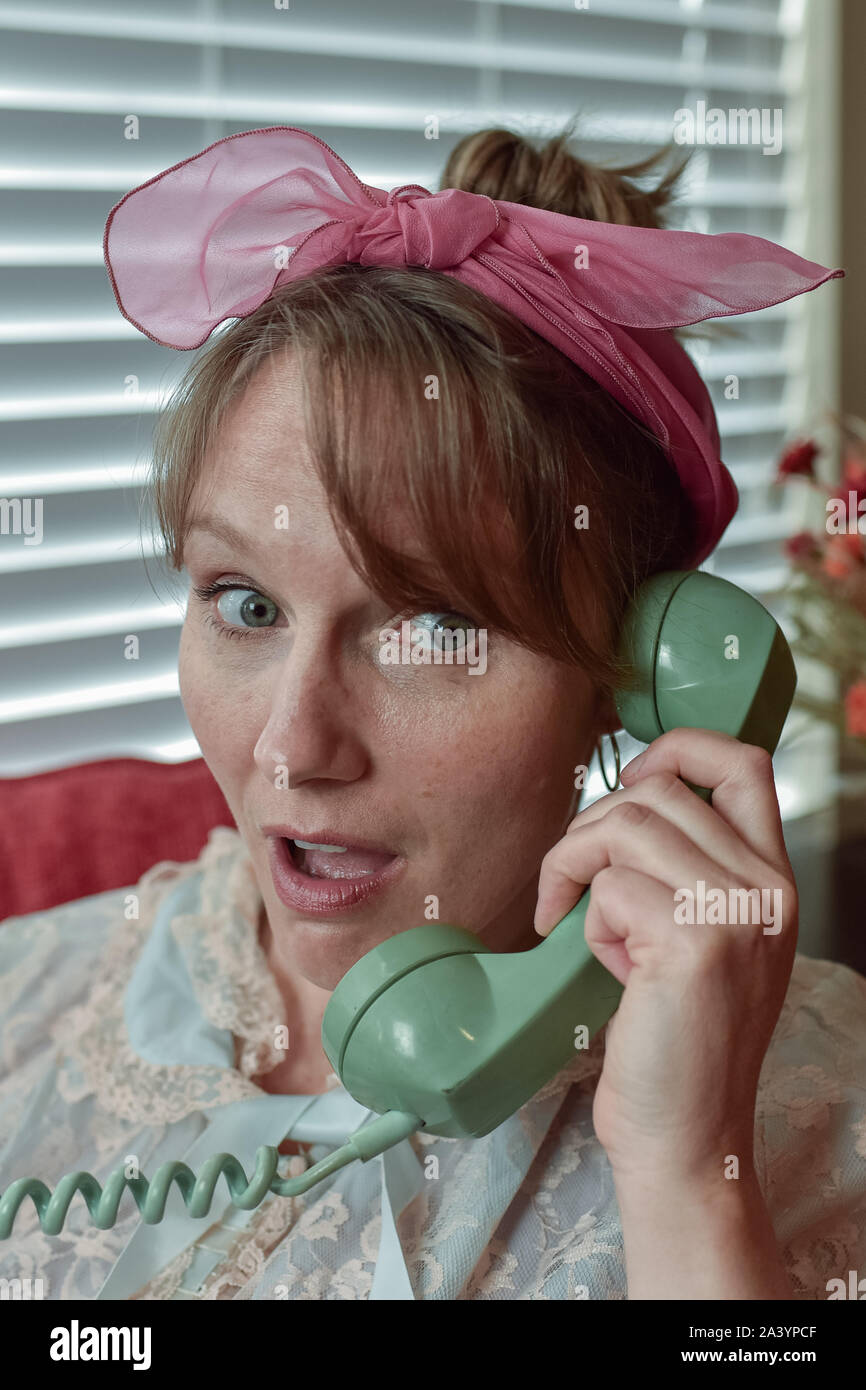 A vintage concept of a nosy, busybody, middle-aged woman with an old-school telephone engaged in delicious gossip! Stock Photo