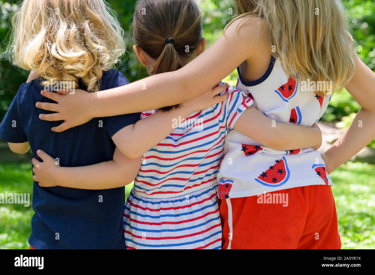 Rear view of children with their arms around each other Stock Photo