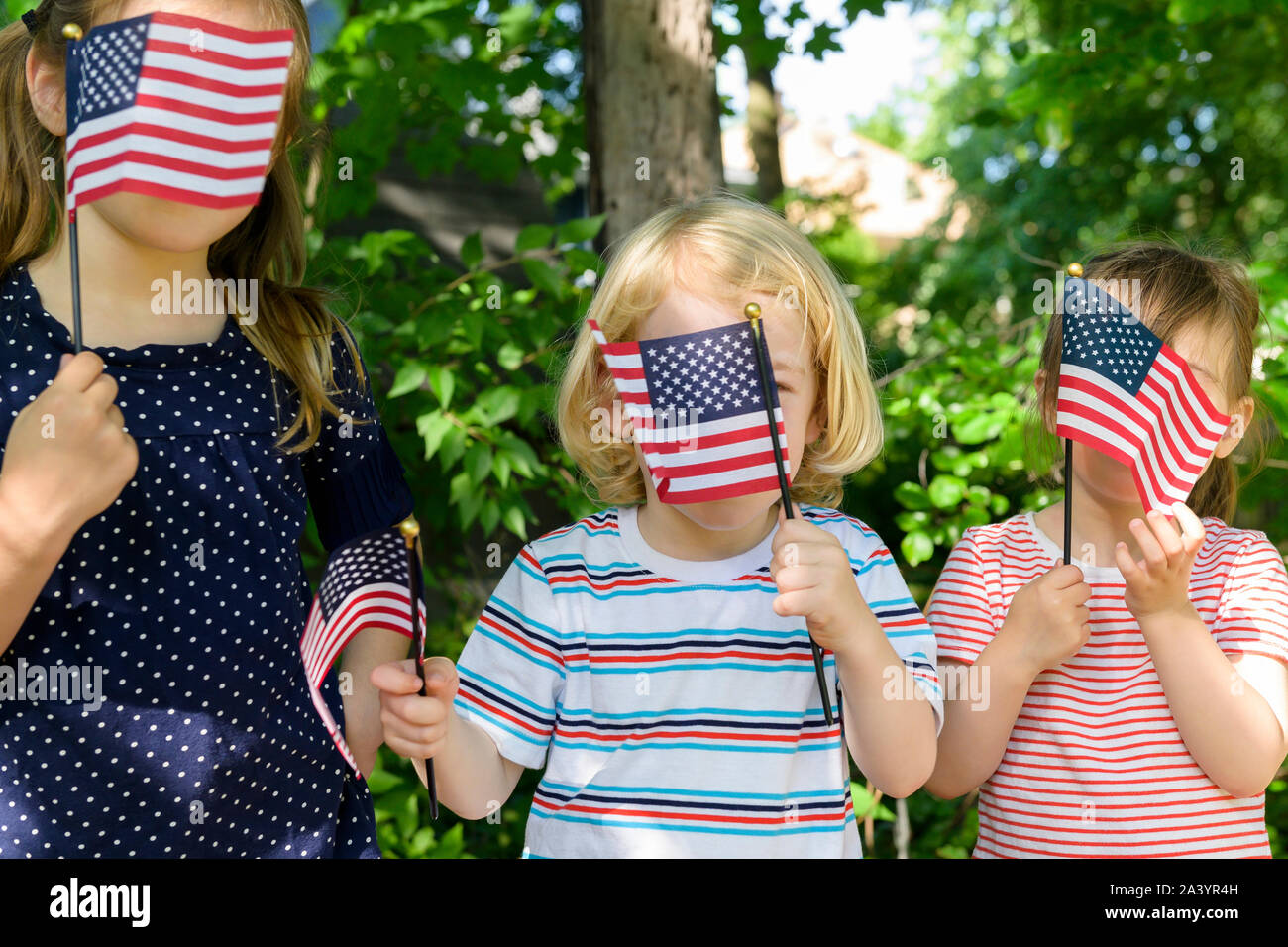Children holding American flags over their faces Stock Photo