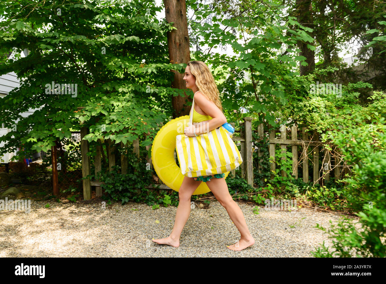 Young woman carrying yellow inflatable and bag Stock Photo