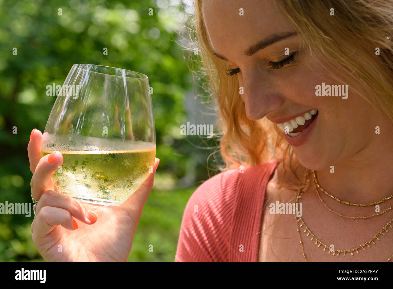 Smiling young woman holding glass of white wine Stock Photo