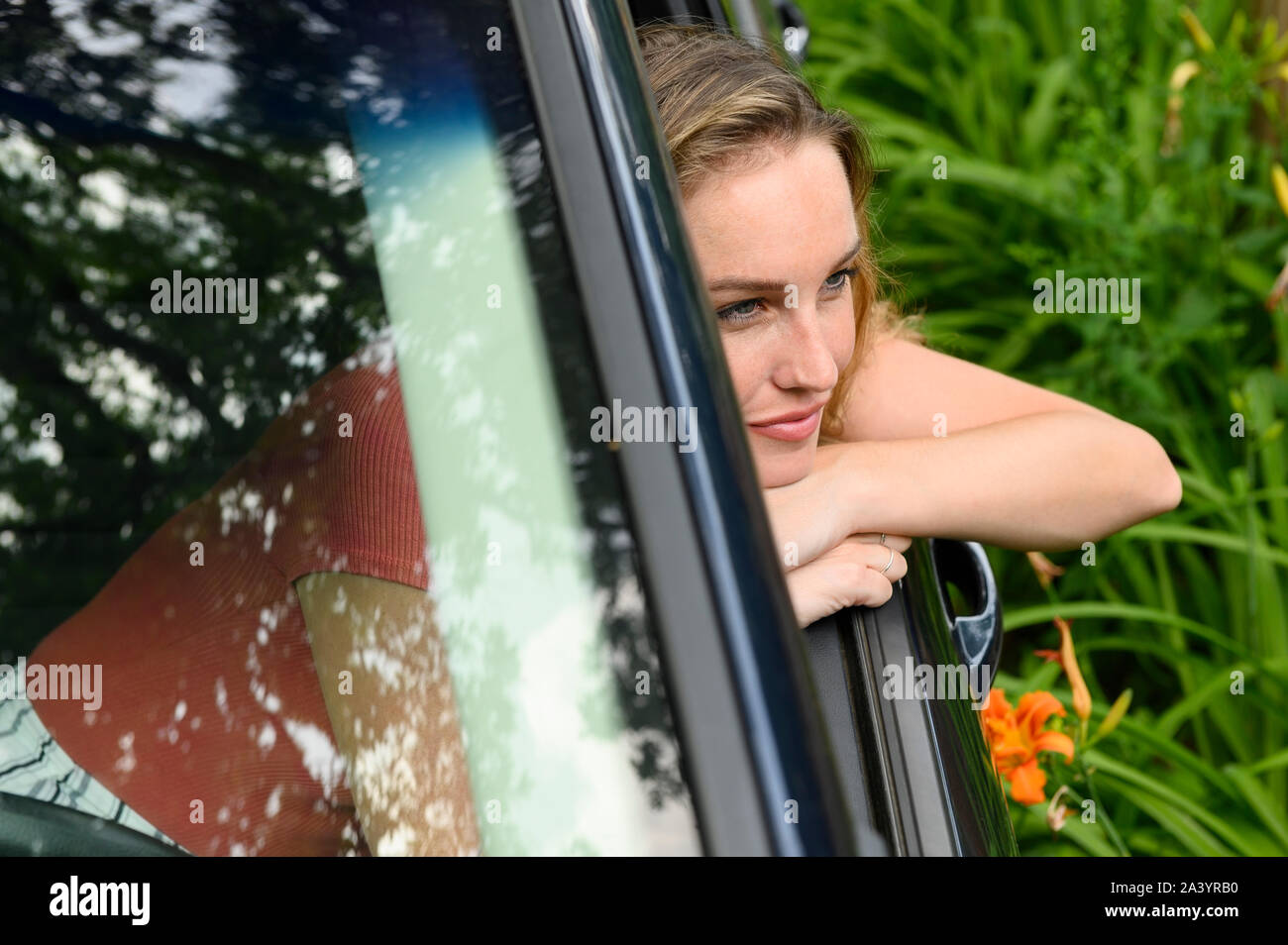 Young woman leaning out of car window Stock Photo