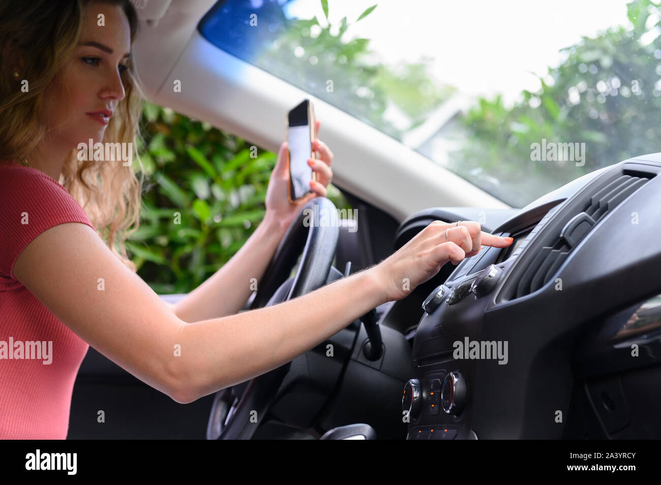 Young woman using smart phone and touchscreen in car Stock Photo