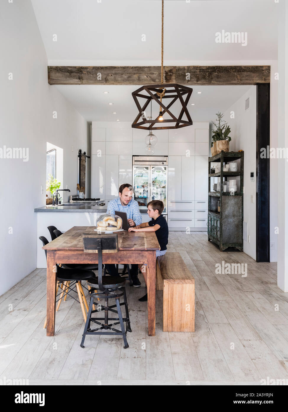 Father and son using digital tablet at dining table Stock Photo