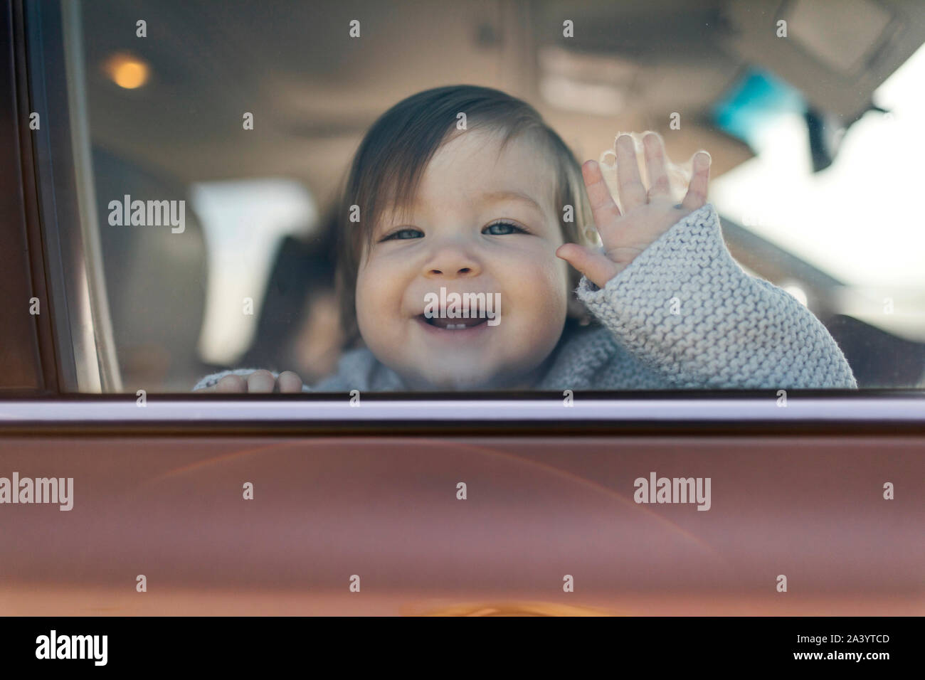 Smiling baby girl behind car window Stock Photo