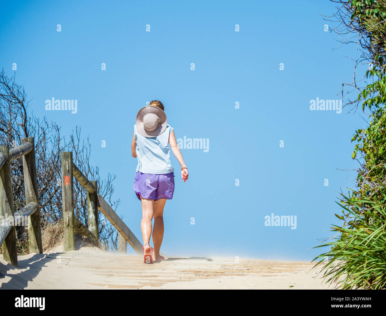 Rear view of woman walking on boardwalk Stock Photo