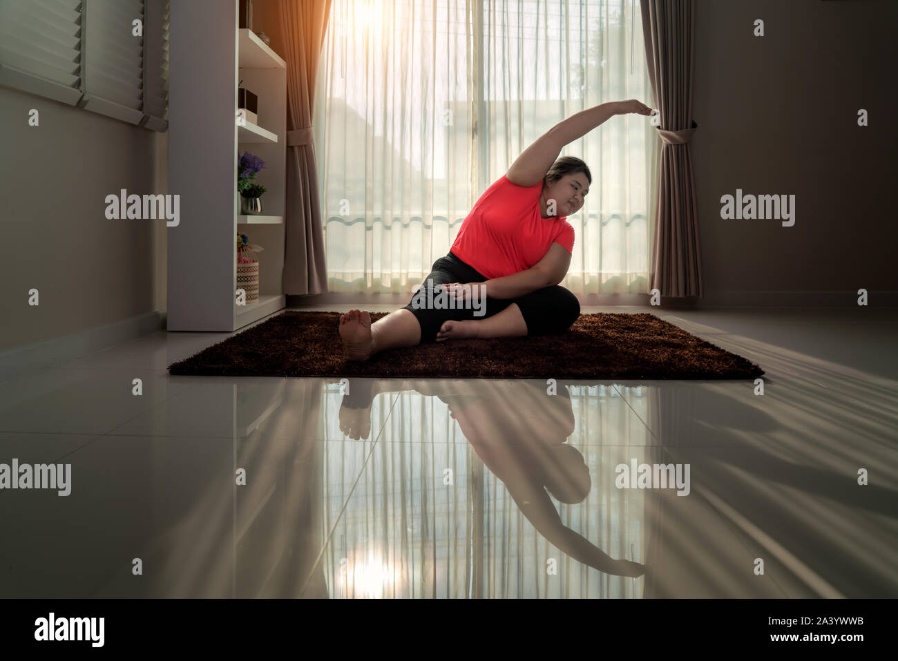 Asian Overweight woman exercising yoga Seated side bend pose alone on the floor in house, yoga meditation exercise at home. Fat women take care of hea Stock Photo