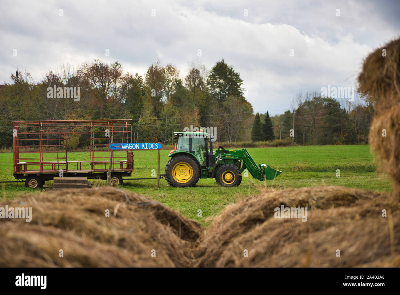 Wagon ride tractor waiting behind rolls of hay Stock Photo