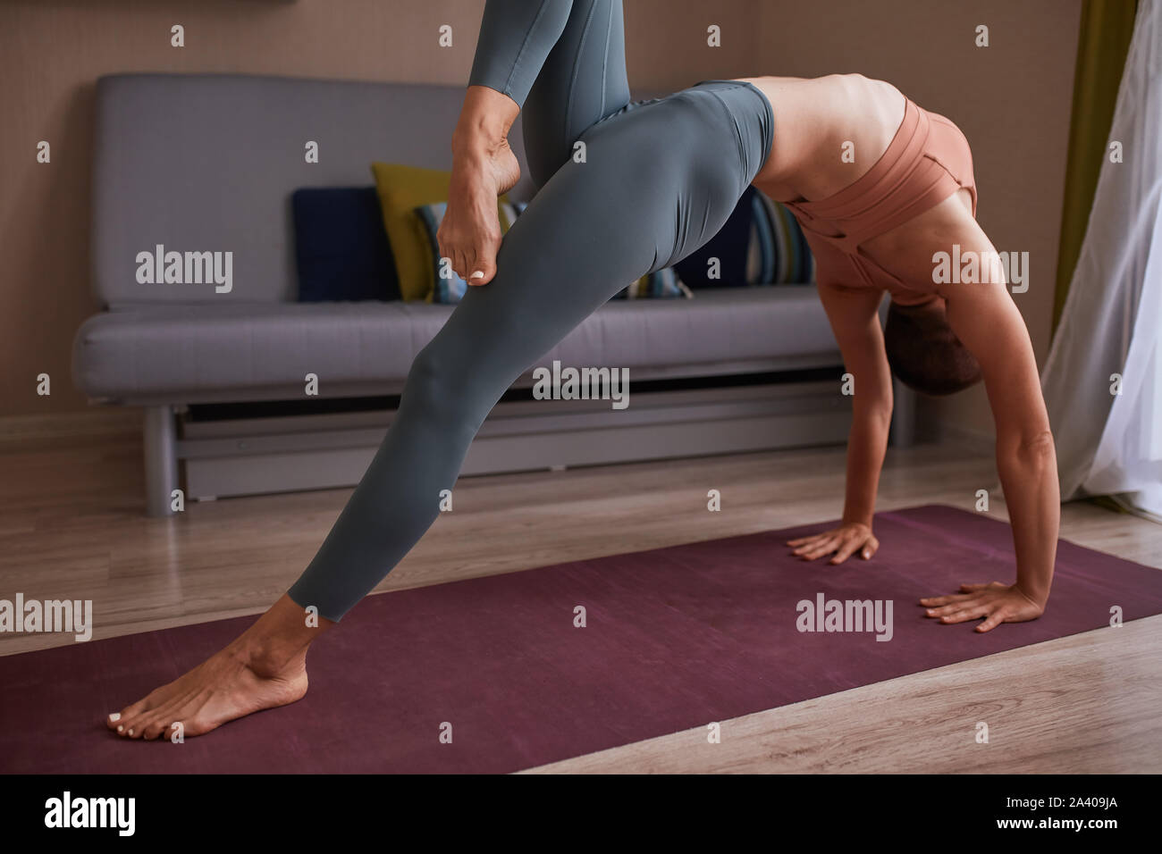 Young short-haired woman in grey leggins doing bridge exercise on purple  mat, warming up muscles before practicing yoga at home. One leg is raised  Stock Photo - Alamy