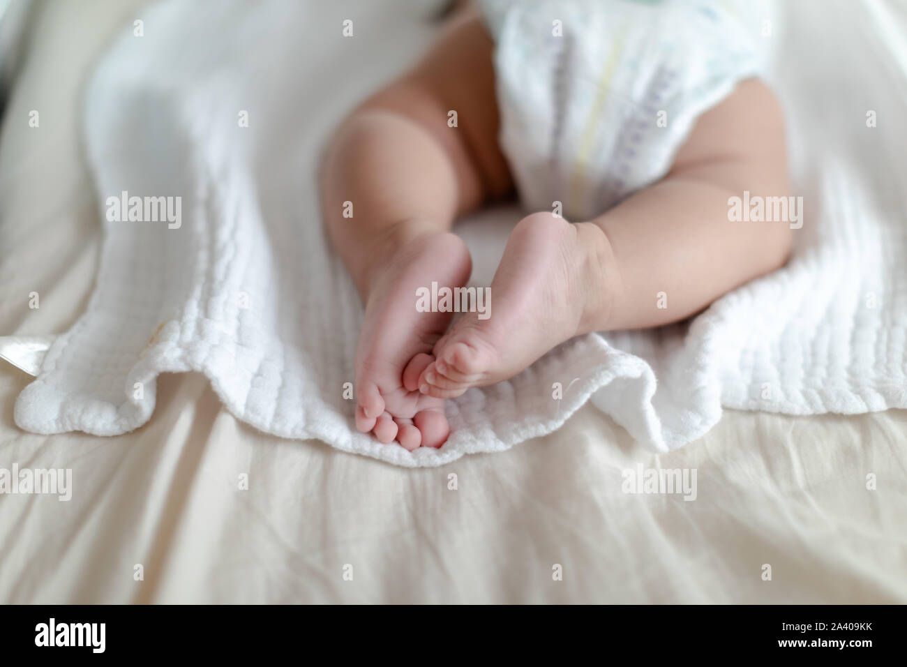 4 months old baby wearing diapers lying on the bed at home Stock Photo