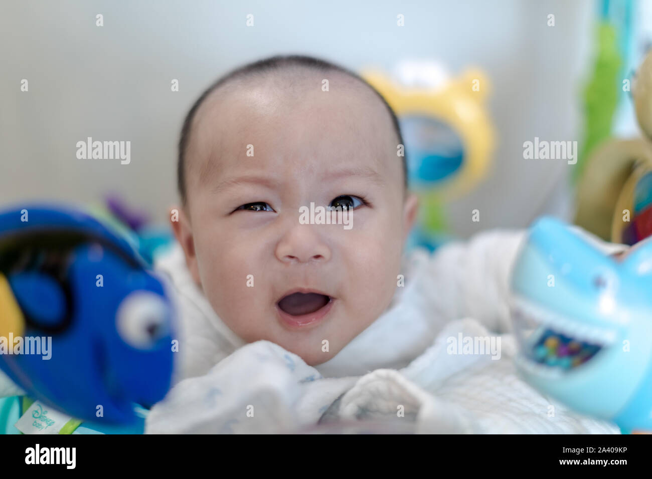 Funny baby boy winking at camera around toys Stock Photo