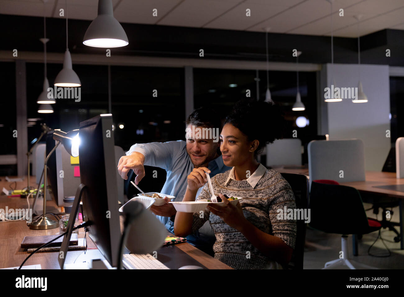 Two young creative professionals working late in a modern office Stock Photo