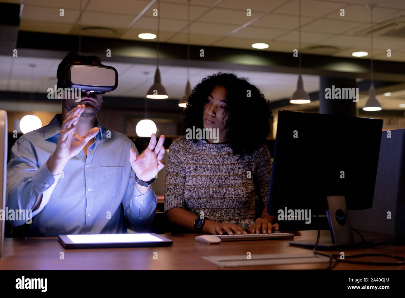 Two young creative professionals working late in a modern office using VR Stock Photo