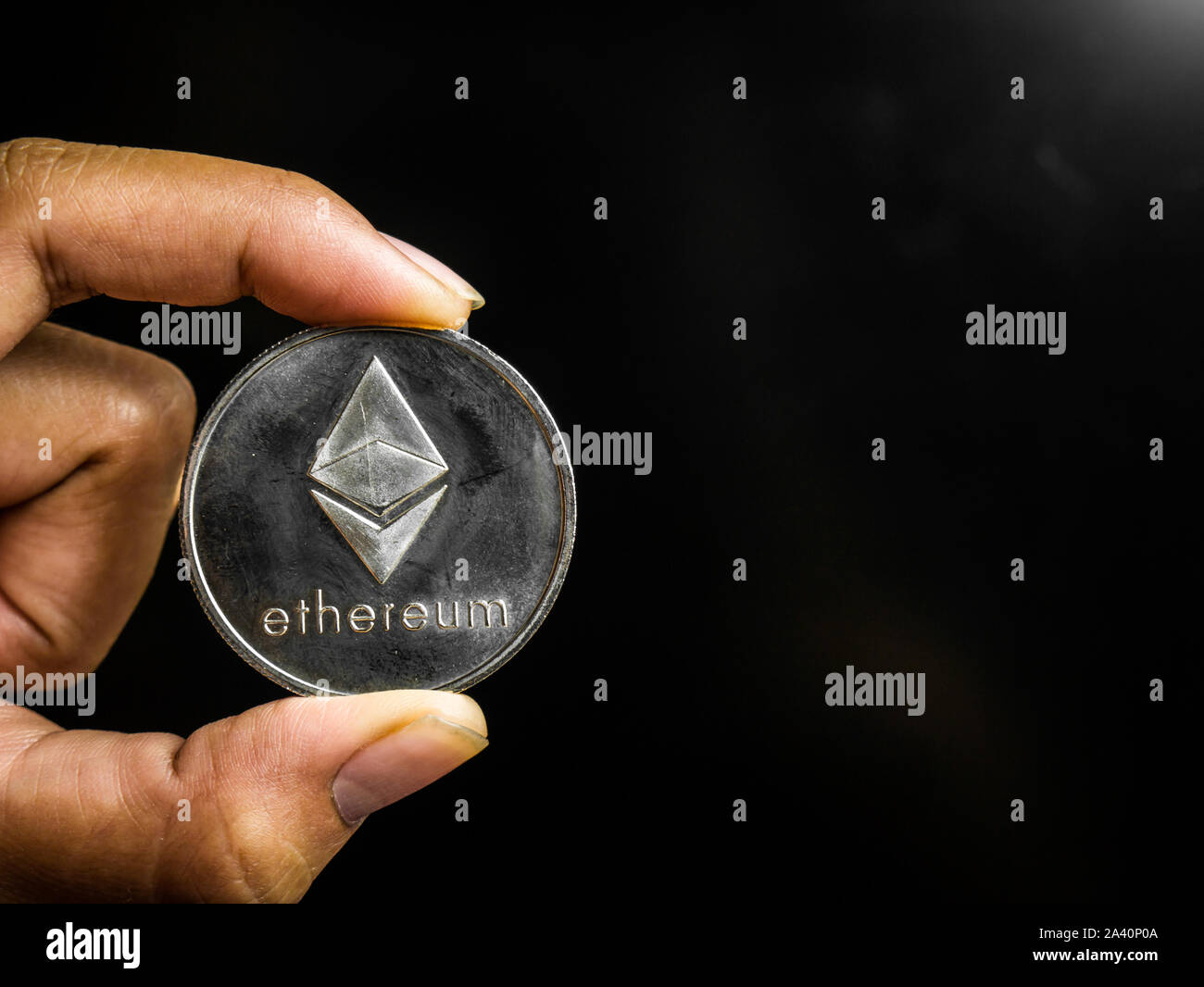 Hand is holding silver ethereum coin on a black screen. Business value  cryptocurrency are expensive Stock Photo - Alamy
