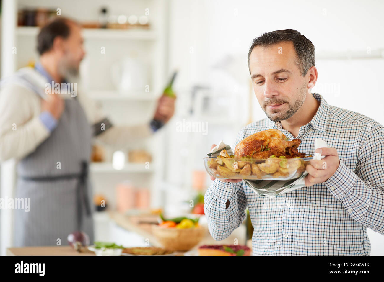 Young and matue men holding tray with homemade roasted turkey over