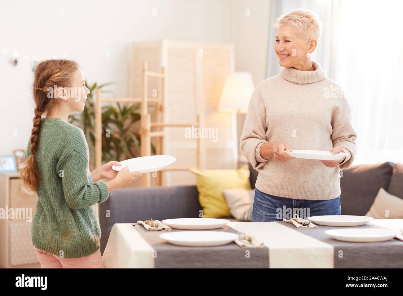 Mother and daughter serving the dining table together and preparing for
