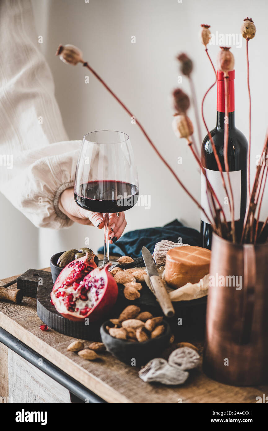 Womans hand holding glass of red wine over various snacks Stock Photo ...