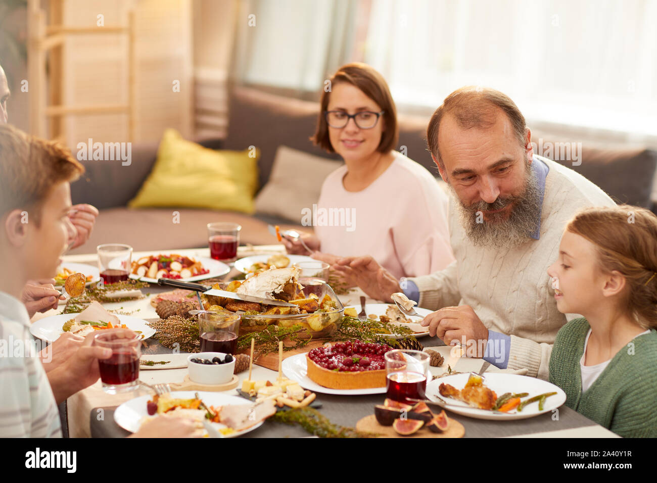 Happy Family Sitting At Dining Table And Talking To Little Girl During Holiday Family Dinner At Home Stock Photo Alamy