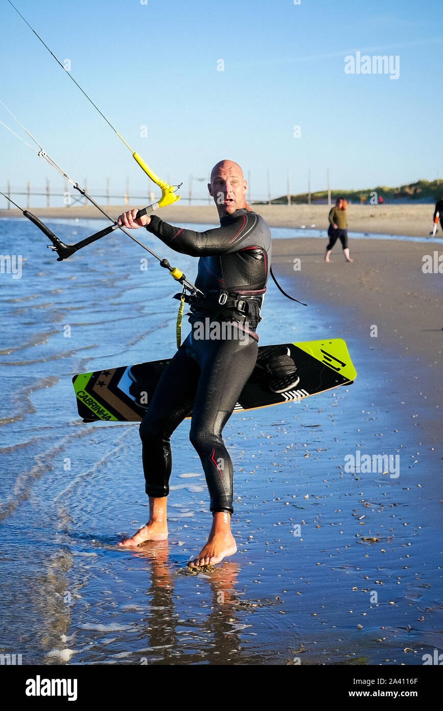 Close up of a man holding onto a Naish kite and twin tip board on the beach  in Texel in The Netherlands Stock Photo - Alamy