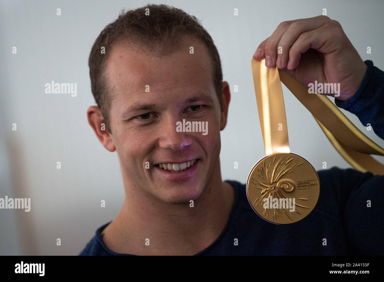 11 October 2019, Baden-Wuerttemberg, Stuttgart: Fabian Hambüchen with the gold medal of the Turn - WM 2019, which shines. In Weinstadt near Stuttgart the glowing medals for the Gymnastics World Championships are finished. Hambüchen signed the medal of this year's high bar world champion on the inside and assembled it independently. Photo: Tom Weller/dpa Stock Photo