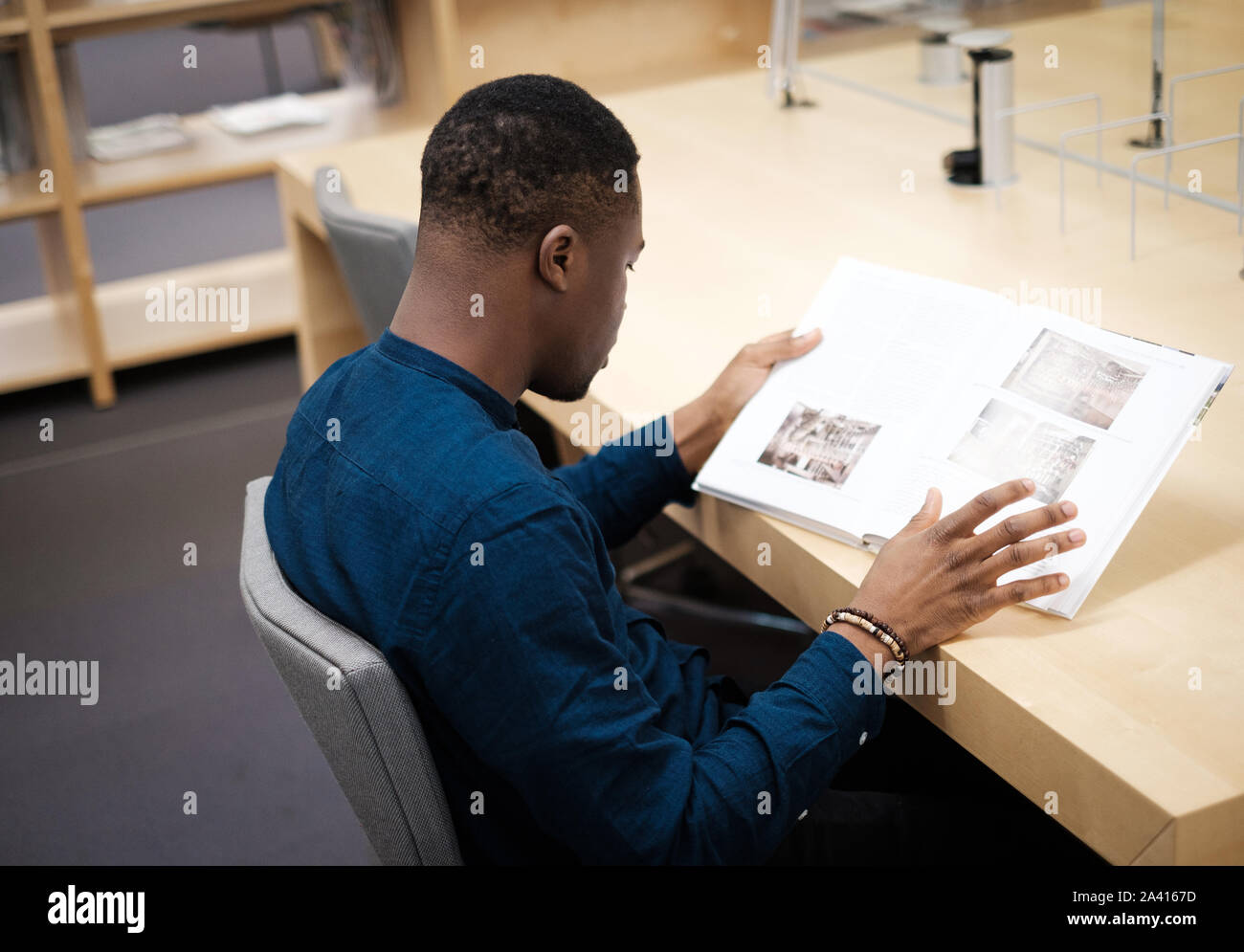 Young man reading book in public library Stock Photo Alamy