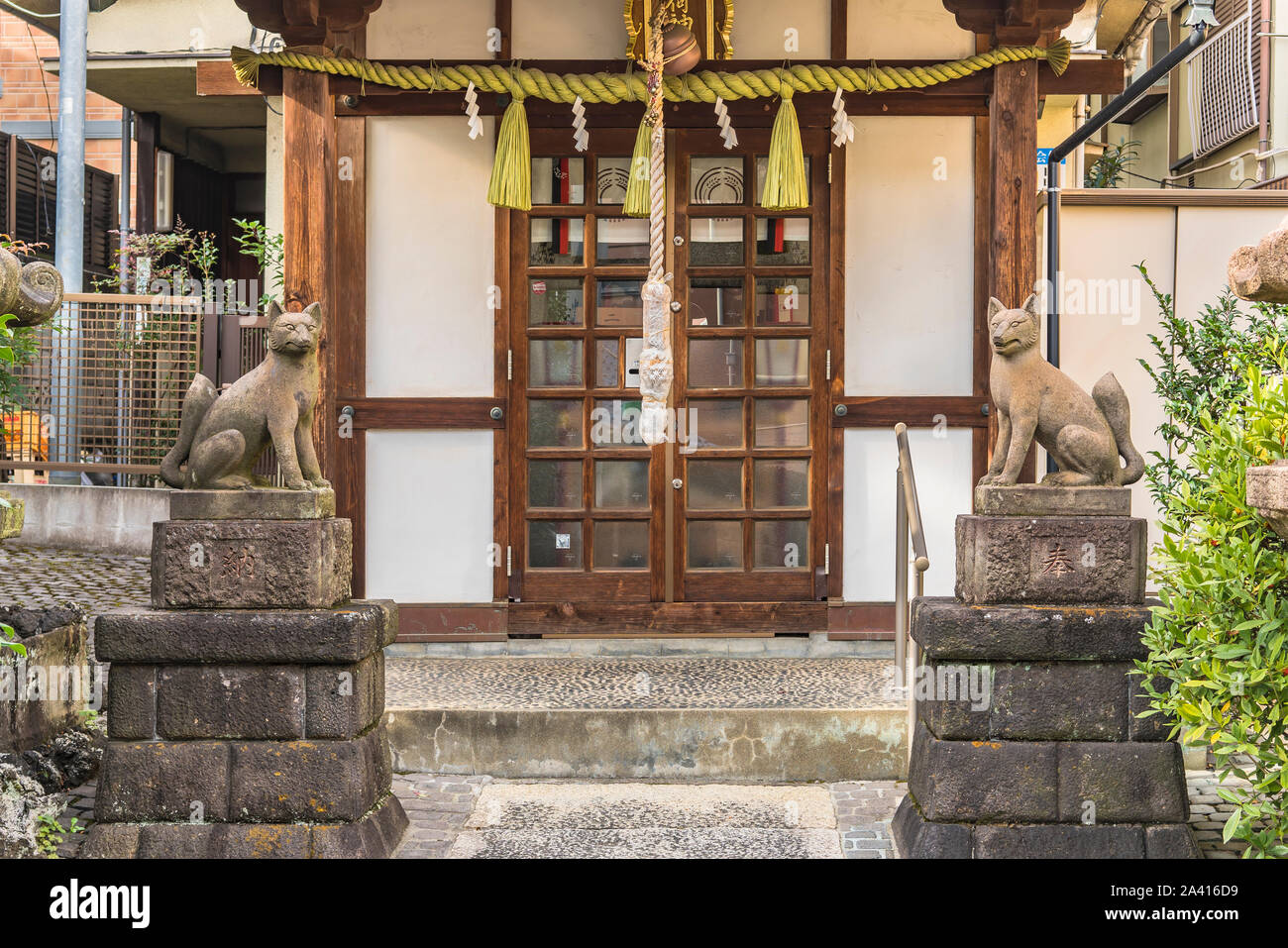 Two statues of foxes inari, deity of rice in the Shinto shrine of Mejiro Toyosaka Inari Jinja in Tokyo. Stock Photo