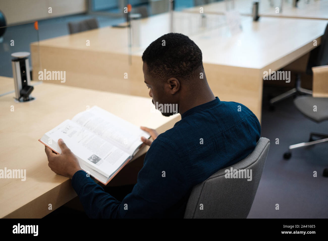 Young man reading book in public library Stock Photo Alamy