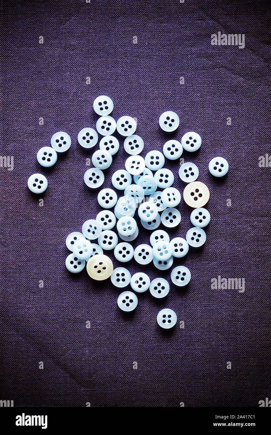 A scattered pile of light blue buttons on a dark blue background Stock Photo