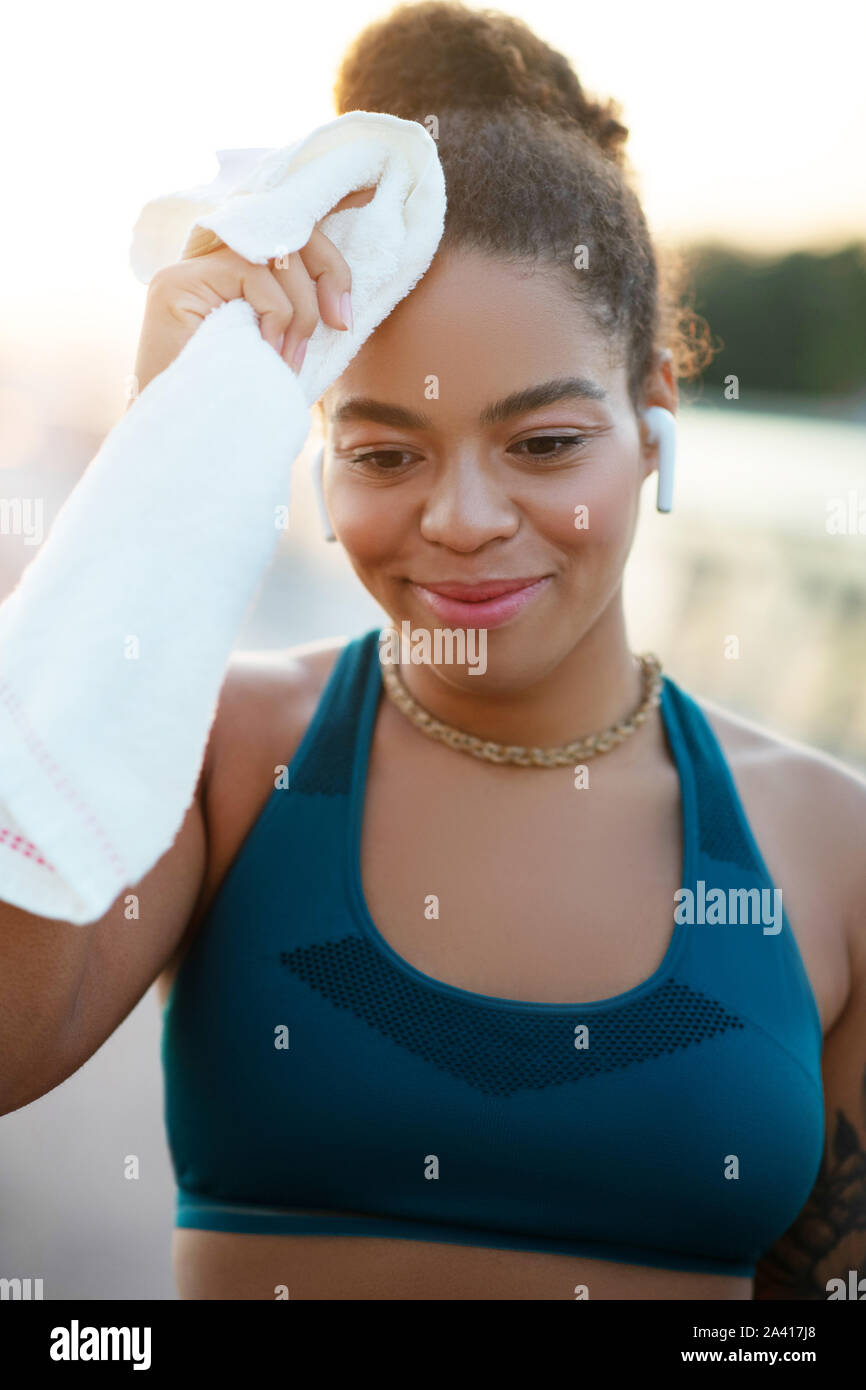 Young woman drying her sweat on forehead after intensive run Stock Photo