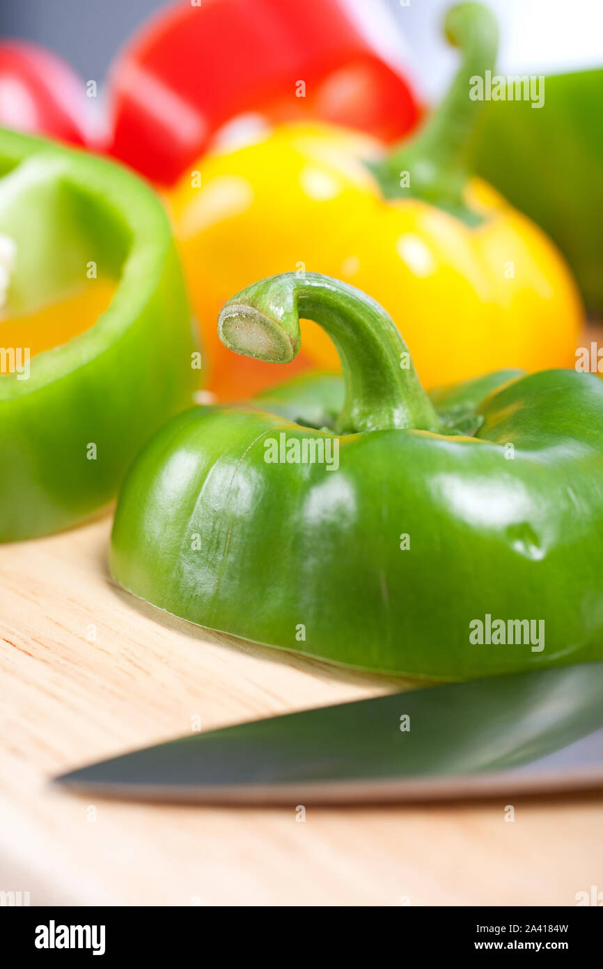 Selection of red green and yellow peppers sliced up on a chopping board ...