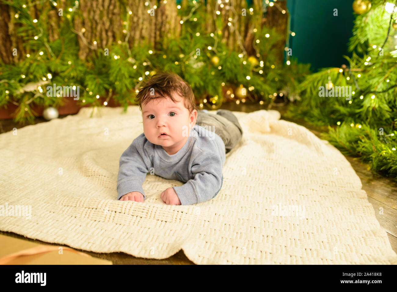 A child near the Christmas tree. Little boy celebrating christmas. baby's first christmas. Stock Photo