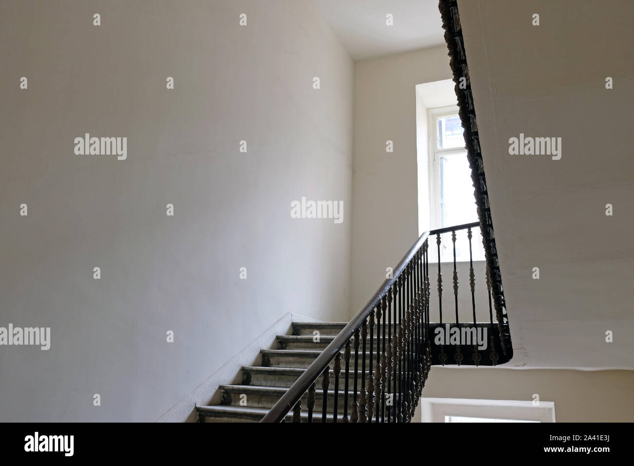 Staircase in the entrance of the house. White walls, railings in the stairwell and steps up. Stock Photo