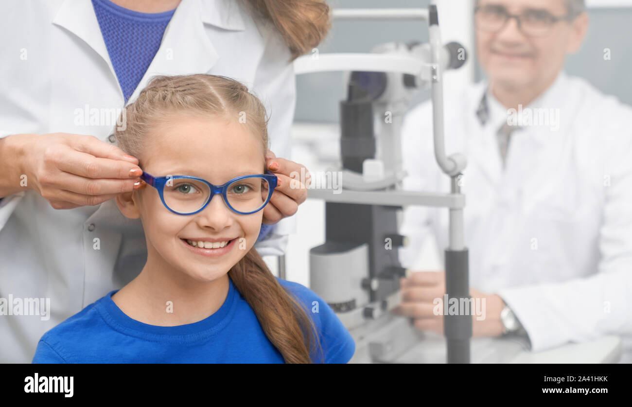 Front view of happy girl wearing new glasses in optical store. Pretty