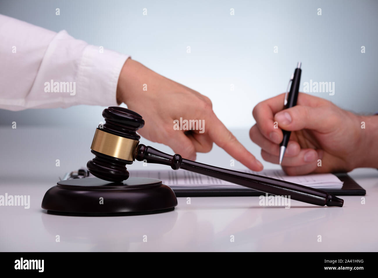 Mallet And Sound Block In Front Of Attorney Advises The Client To Sign On Agreement Stock Photo