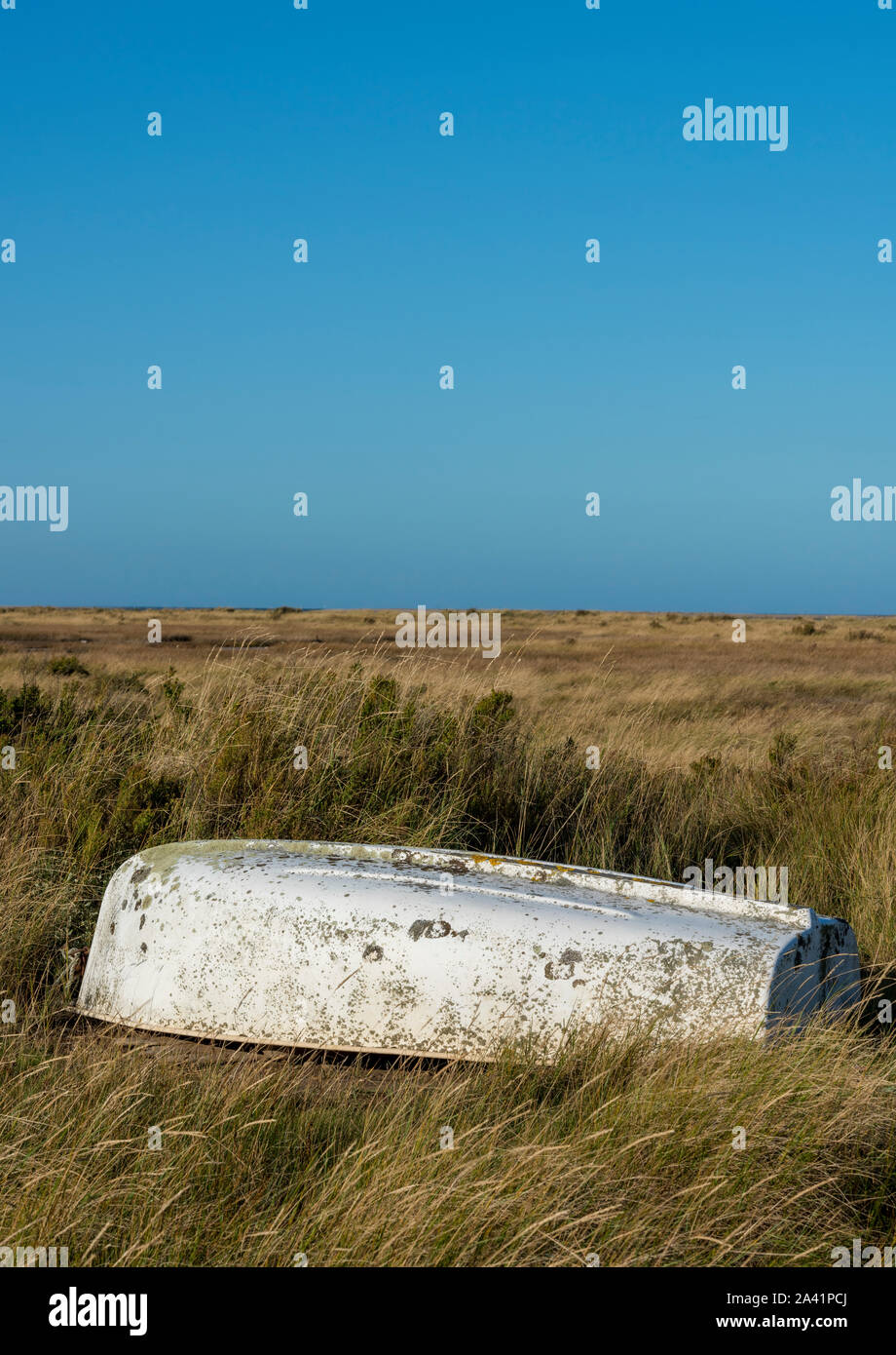 An old upturned rowing boat on the salt marshes at Morton on the north norfolk coast, east Anglia, uk. Stock Photo