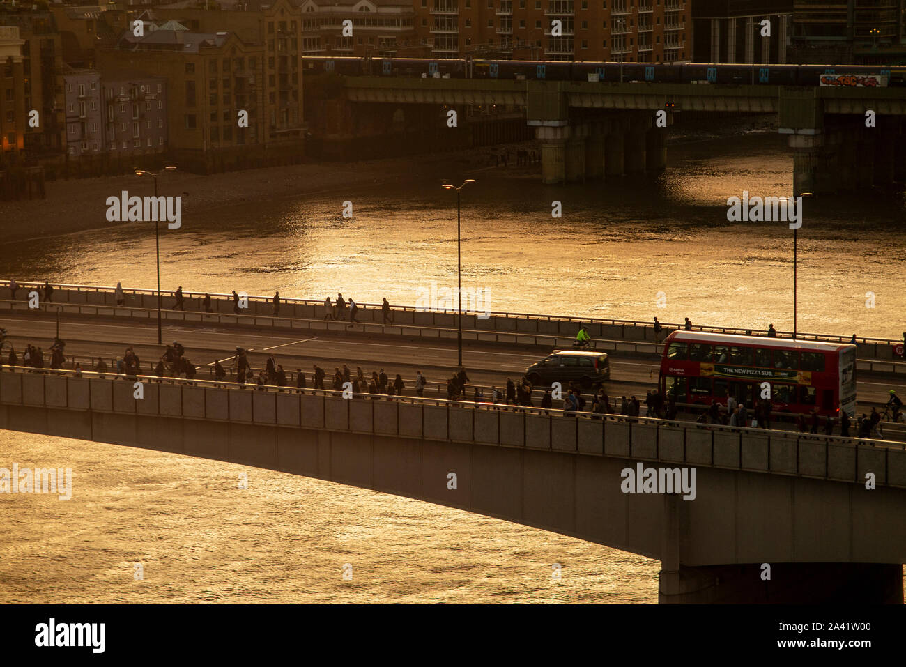 End of the working day and commuters walk over London Bridge as the sun sets Stock Photo