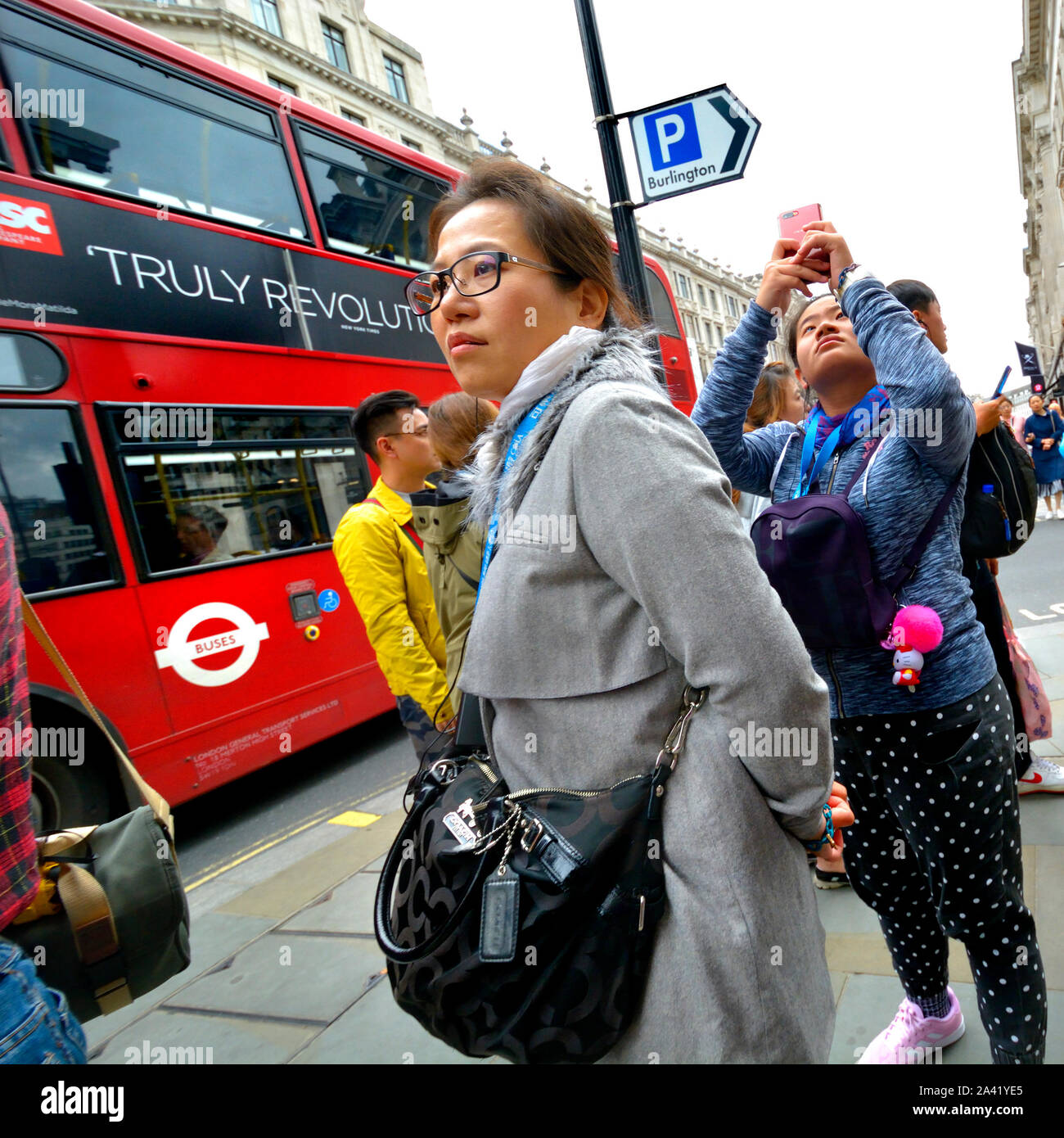 London, England, UK. Asian tourists - one taking a photo on her mobile phone in Piccadilly Stock Photo